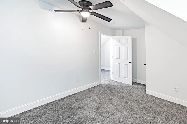 an empty room with a ceiling fan and carpet