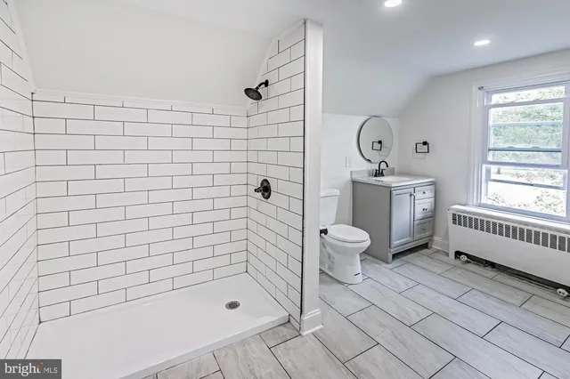 a bathroom with a bathtub shower sink mirror and toilet