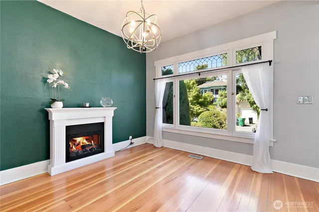 a view of an empty room with wooden floor fireplace and a window