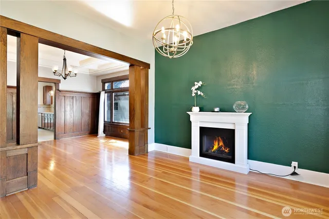 a view of an empty room with wooden floor fireplace and a window