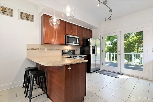 a kitchen with kitchen island granite countertop a stove top oven a sink dishwasher a dining table and chairs with wooden floor