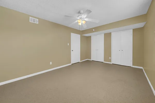 a view of an empty room with a chandelier fan