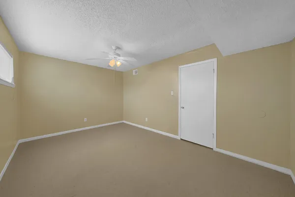 an empty room with a ceiling fan and a window