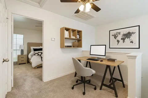 a view of a workspace with furniture and a ceiling fan