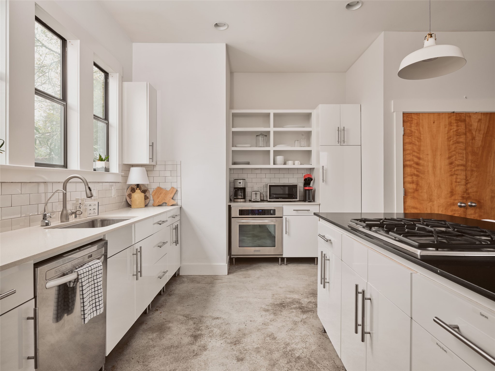 2002 East 13th Street, Unit A Austin, TX 78702 - Photo 14 of 37 Kitchen featuring stainless steel appliances, open shelves, white cabinets, hanging light fixtures, and dark stone counters
