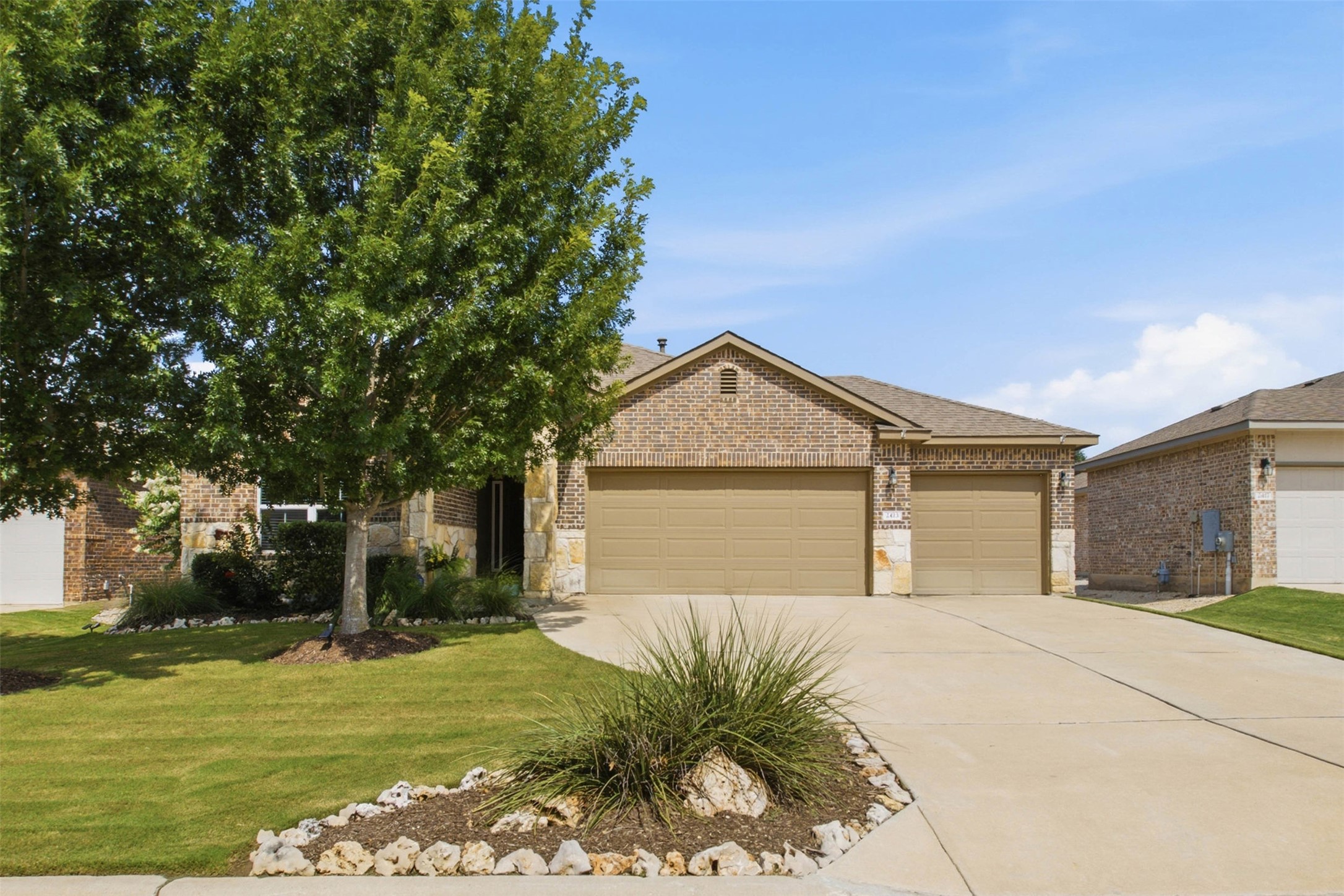 2413 Bridges Ranch Road Georgetown, TX 78628 - Photo 1 of 31 A welcoming brick and stone facade home offers a spacious driveway and attached garages.