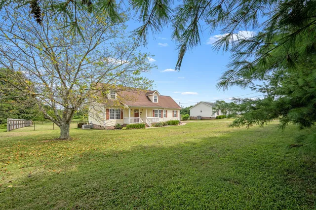 a view of a big house with a big yard and large trees