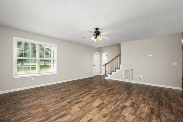 a view of an empty room with a window and a chandelier fan