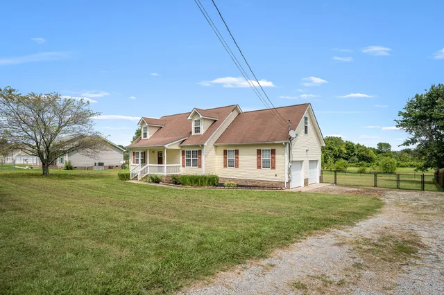 a house that is sitting in the grass with large trees