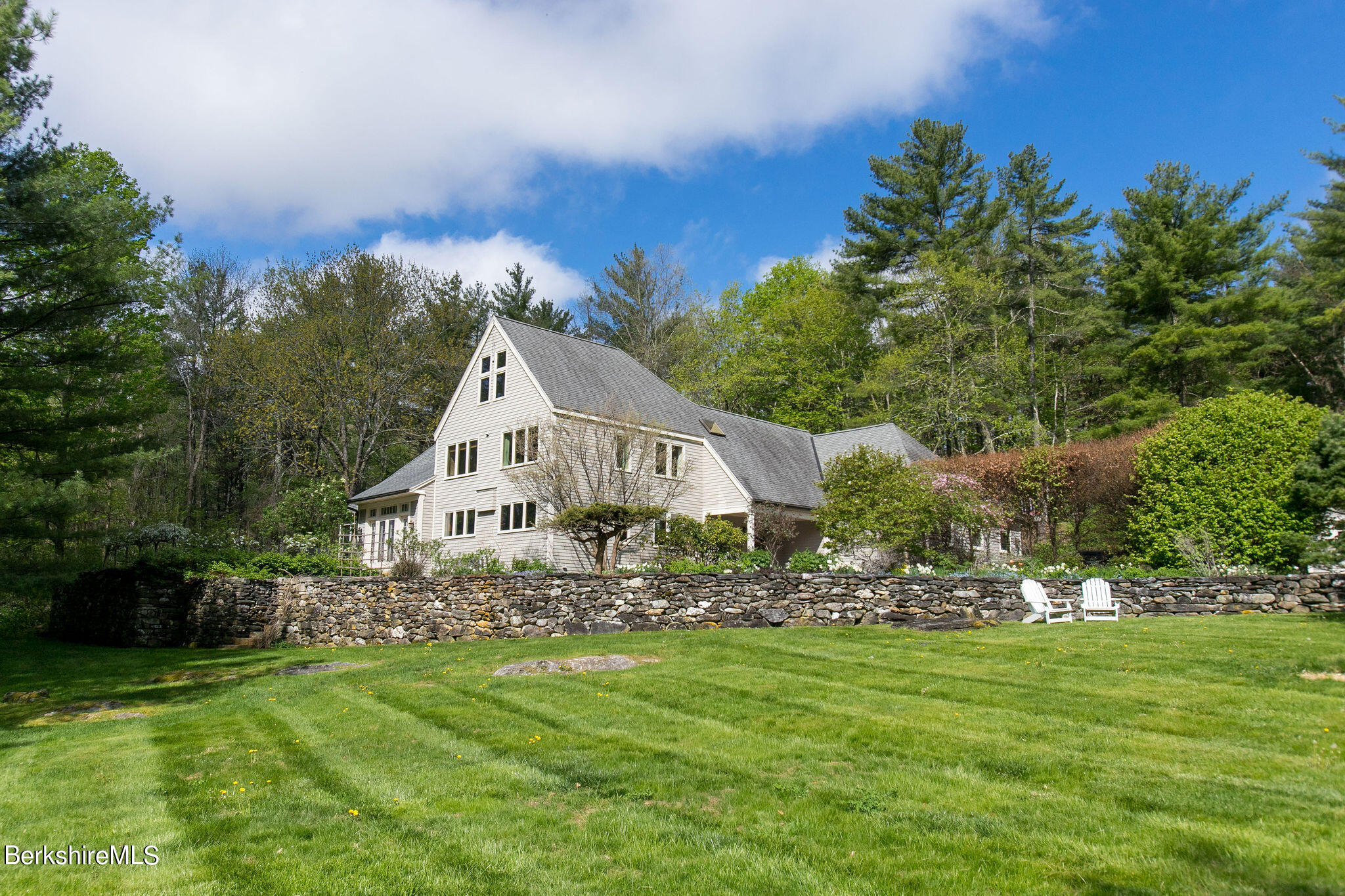 a white house with a big yard and large trees