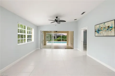 an empty room with windows and chandelier fan