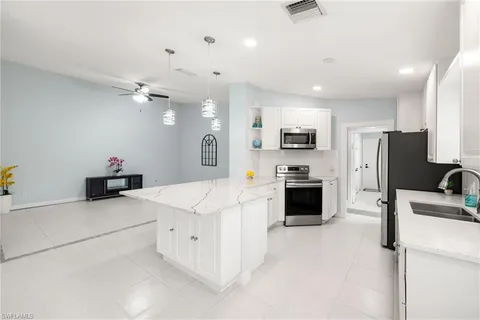 a large kitchen with stainless steel appliances a stove refrigerator sink and a stove