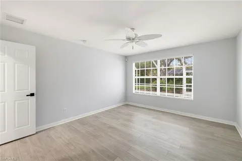 a view of an empty room with a window and wooden floor