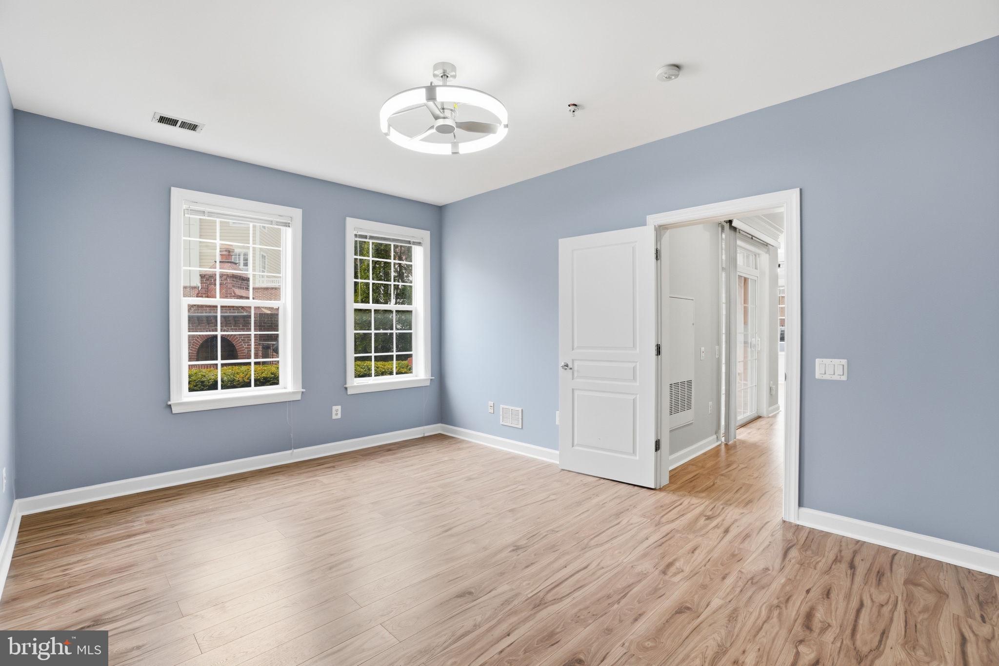 7871 Rolling Woods Court, Unit 1104 Springfield, VA 22152 - Photo 17 of 38 a view of an empty room with a window and wooden floor