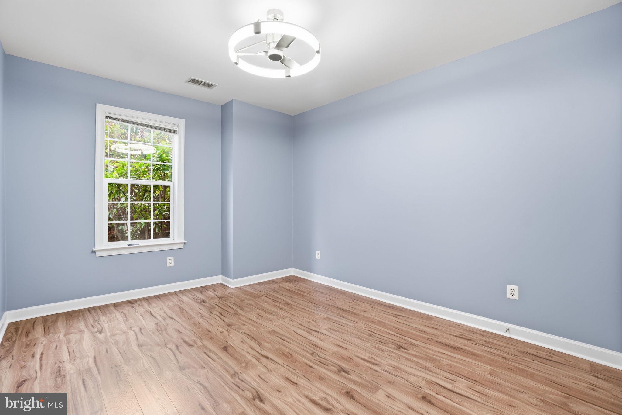 7871 Rolling Woods Court, Unit 1104 Springfield, VA 22152 - Photo 18 of 38 a view of an empty room with wooden floor and a window