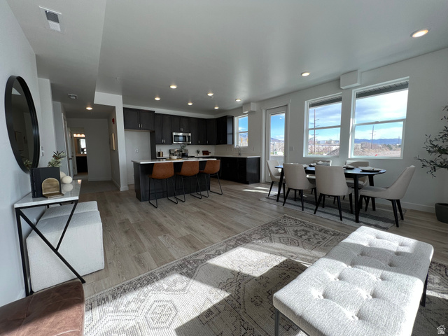 Living area with light wood finished floors and recessed lighting