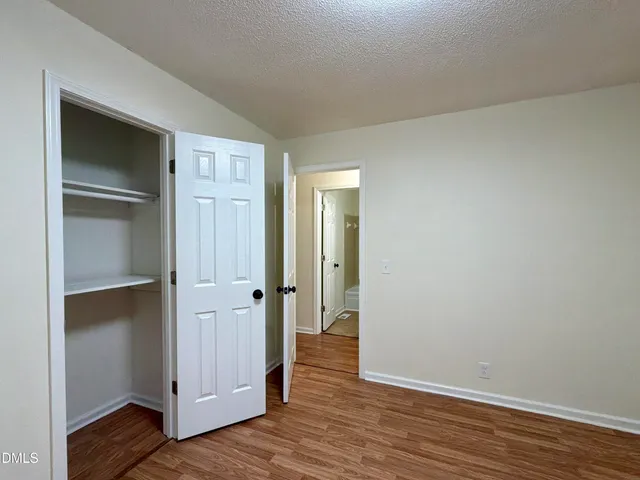 a view of an empty room with wooden floor & closet