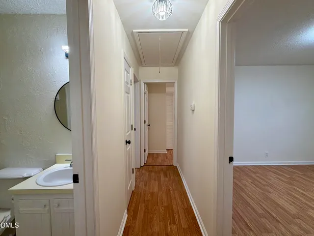 a view of a hallway with wooden floor and a sink