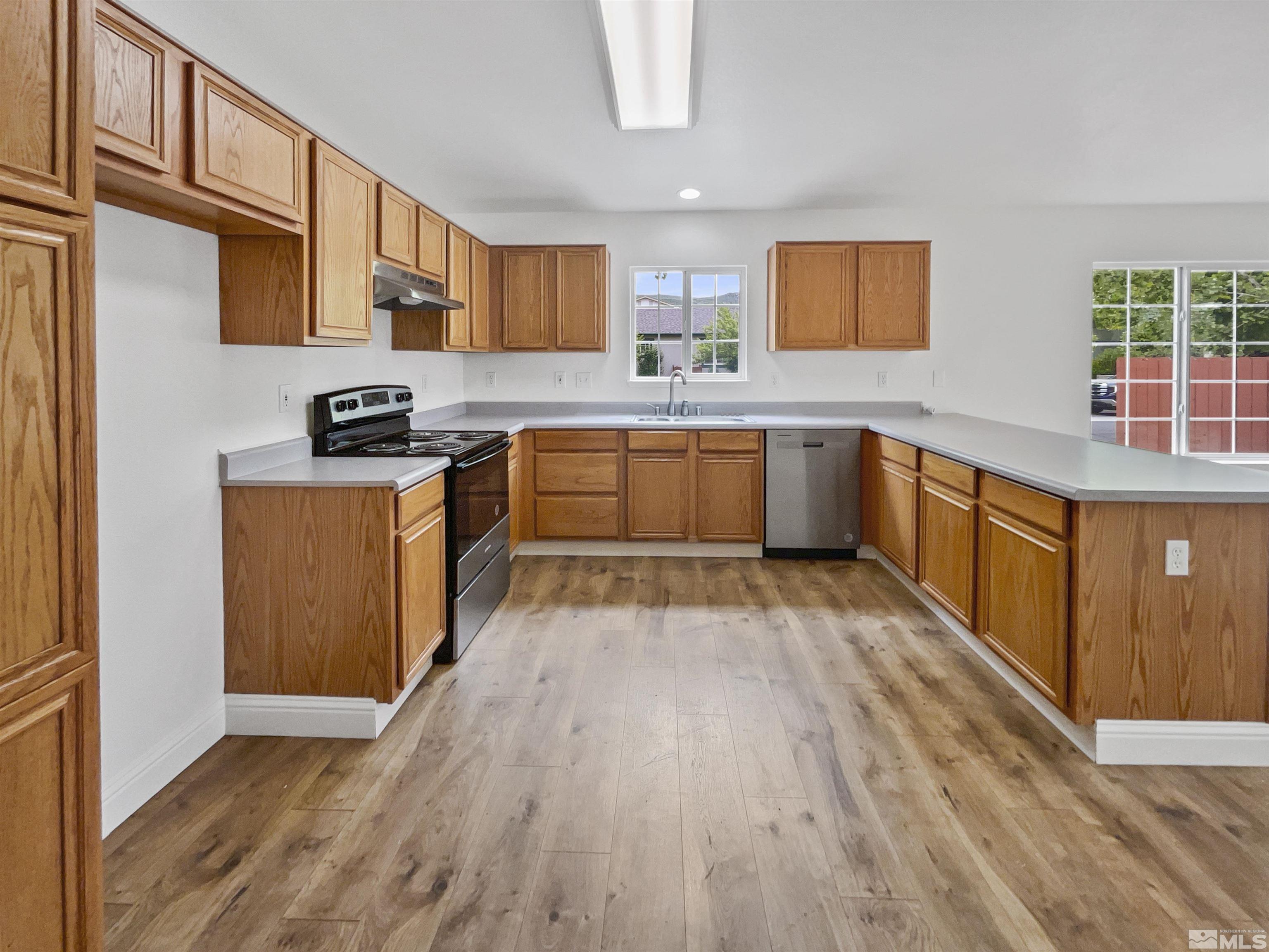 17838 Empire Court Reno, NV 89508 - Photo 17 of 20 a kitchen with stainless steel appliances granite countertop a stove top oven a sink dishwasher and a refrigerator with wooden floor