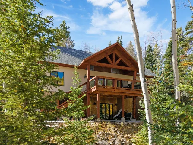 a view of a house with a small yard and large tree