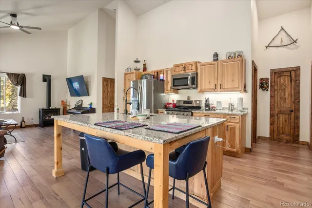 a kitchen with stainless steel appliances granite countertop a table chairs and a refrigerator