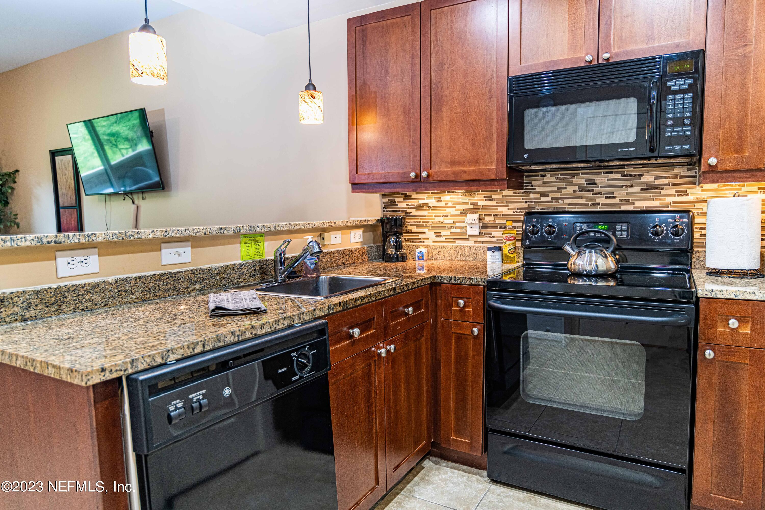 945 Registry Boulevard, Unit 212 St. Augustine, FL 32092 - Photo 5 of 26 a kitchen with stainless steel appliances granite countertop a stove microwave and oven