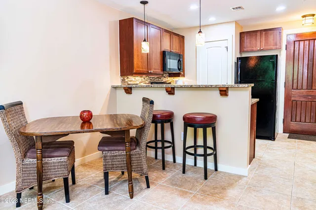 a kitchen with stainless steel appliances kitchen island granite countertop a table chairs and a refrigerator