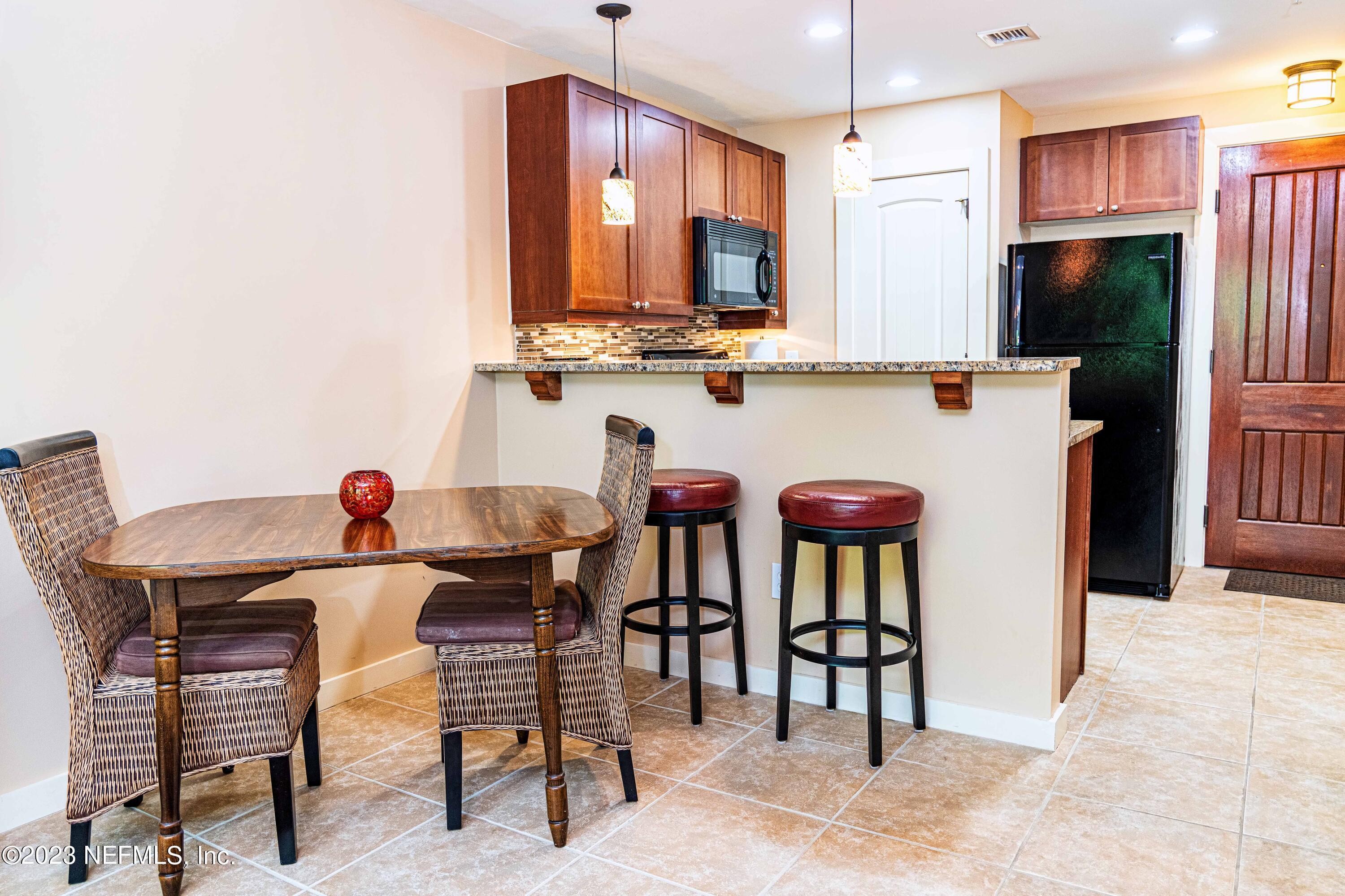 945 Registry Boulevard, Unit 212 St. Augustine, FL 32092 - Photo 6 of 26 a kitchen with stainless steel appliances kitchen island granite countertop a table chairs and a refrigerator