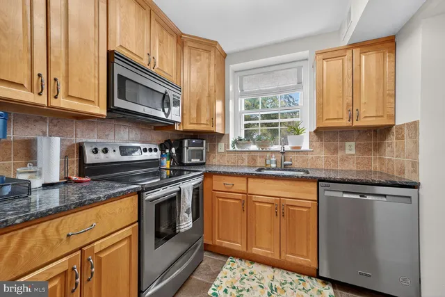 a kitchen with granite countertop cabinets stainless steel appliances a sink and window
