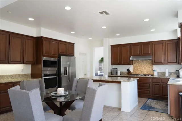 a kitchen with a sink a microwave a refrigerator and chairs