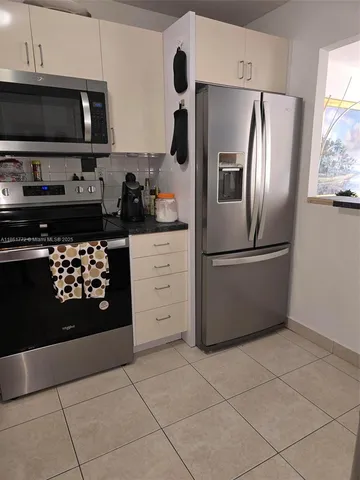 a kitchen with granite countertop a refrigerator and a stove top oven