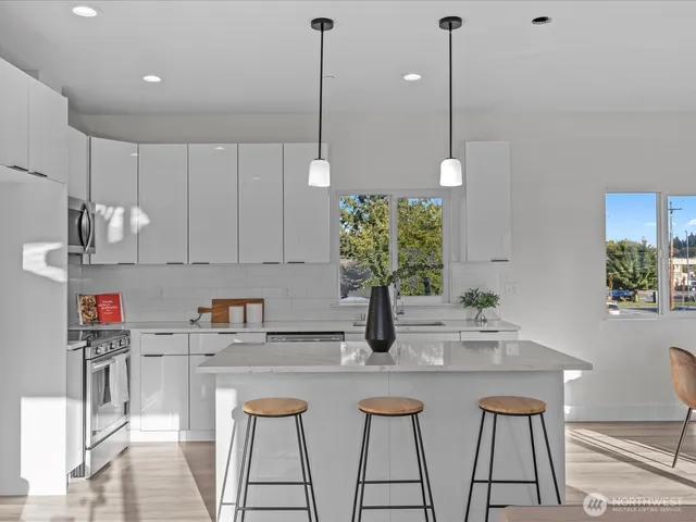 a kitchen with stainless steel appliances granite countertop a sink a stove a microwave a refrigerator and white cabinets