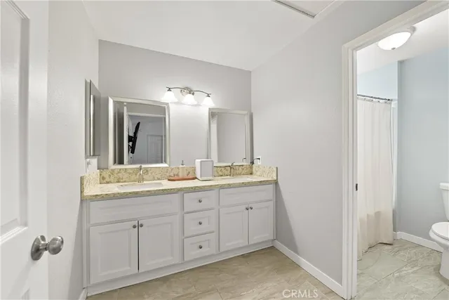 a en suite bathroom with a double vanity sink toilet and a mirror
