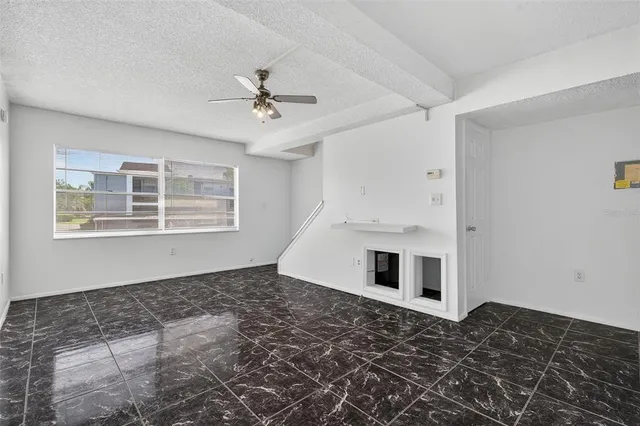 an empty room with a ceiling fan and carpet