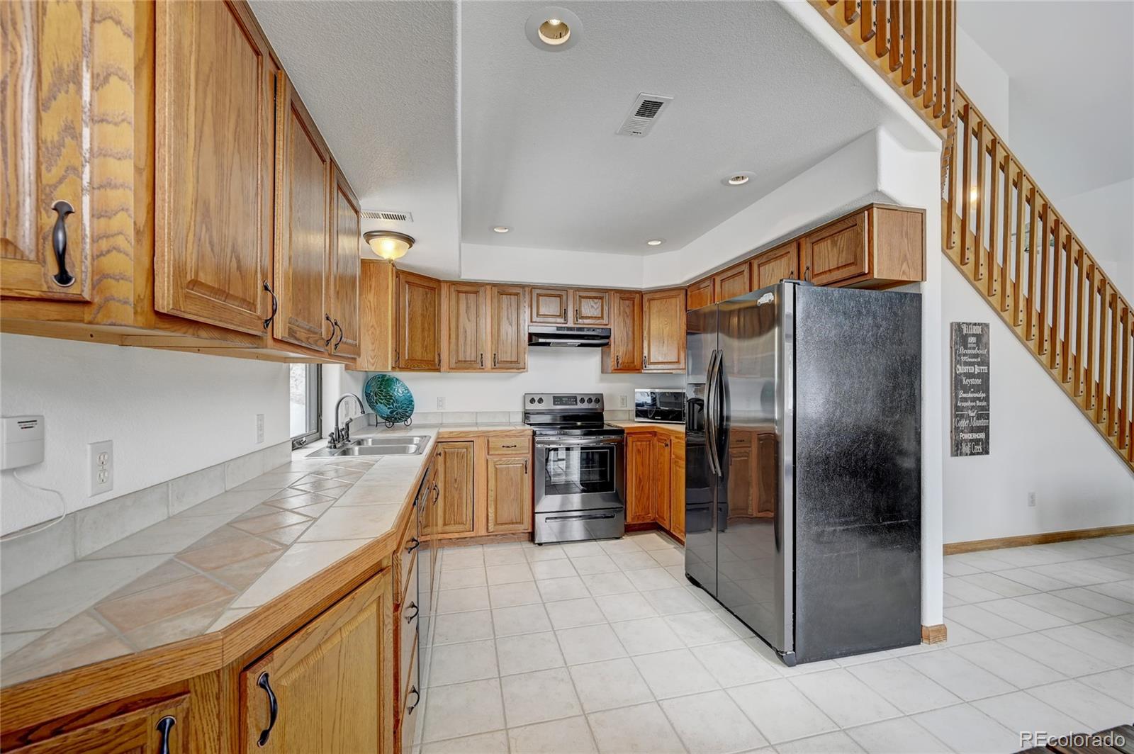 311 North Random Road Bailey, CO 80421 - Photo 15 of 40 a kitchen with stainless steel appliances granite countertop a refrigerator a stove and a sink with cabinets