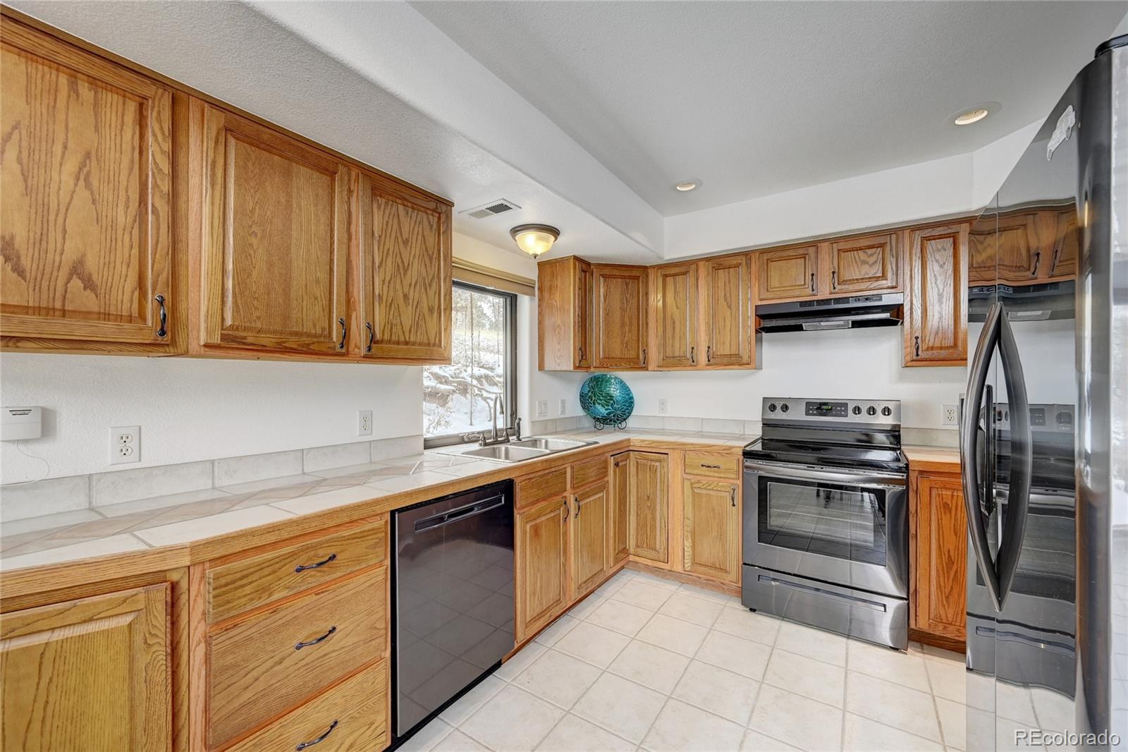 311 North Random Road Bailey, CO 80421 - Photo 16 of 40 a kitchen with stainless steel appliances granite countertop a refrigerator sink and stove