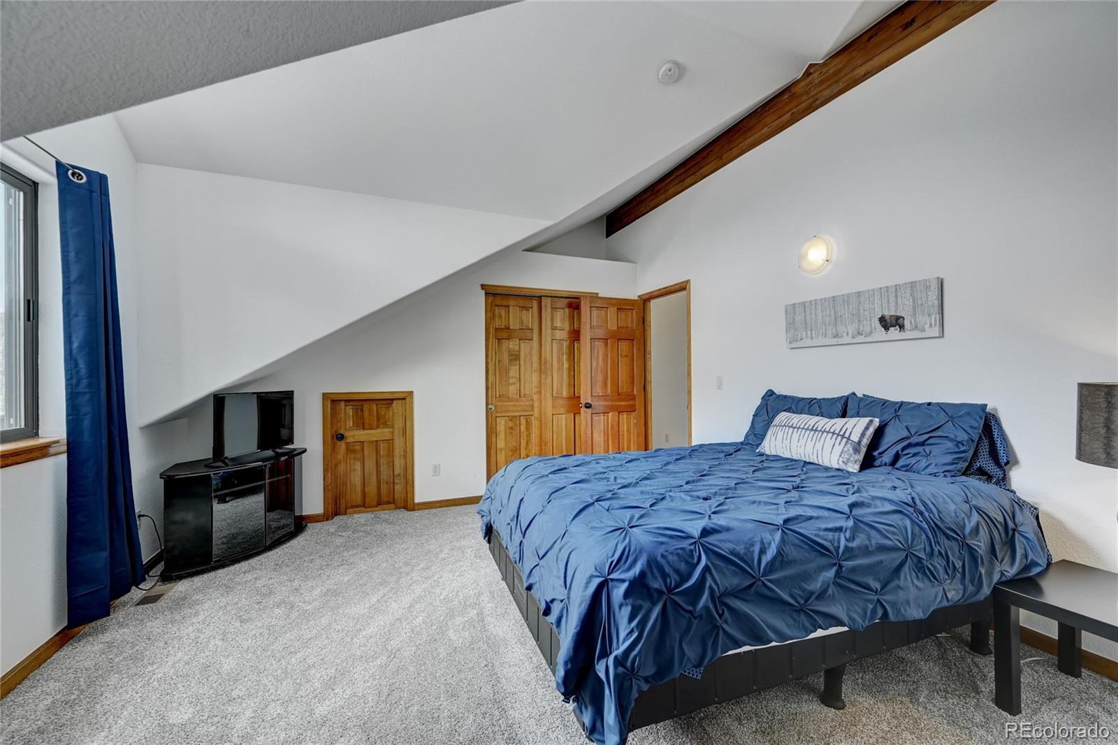 311 North Random Road Bailey, CO 80421 - Photo 31 of 40 a bedroom with a large bed a flat tv screen and dresser