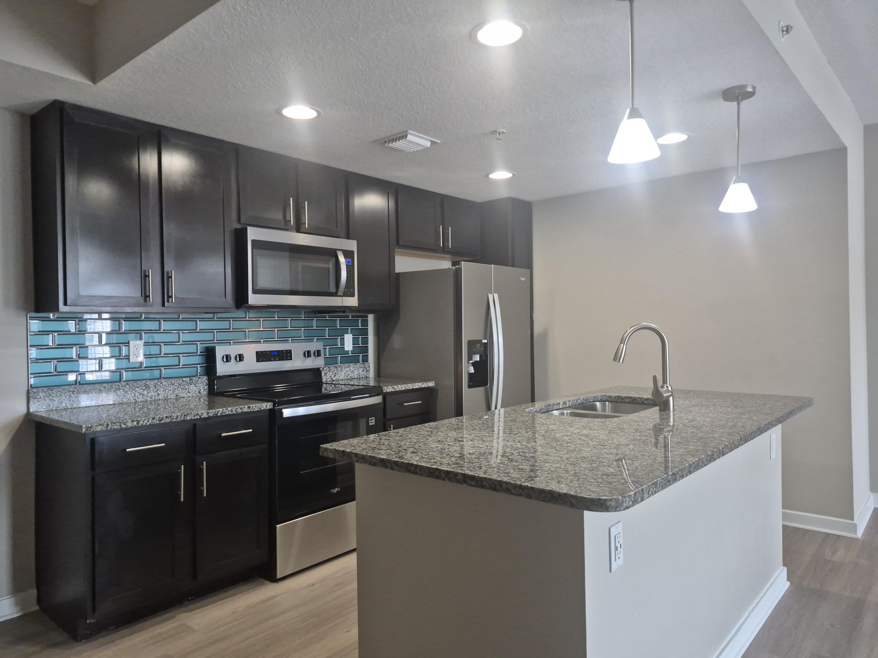 a kitchen with stainless steel appliances granite countertop a sink dishwasher a refrigerator and a microwave