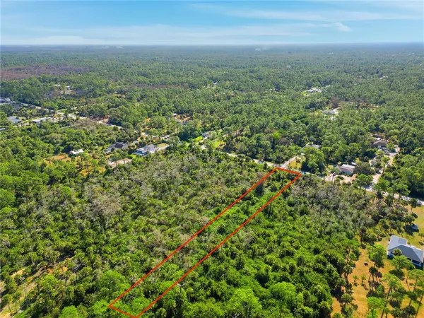 an aerial view of residential houses with outdoor space and trees
