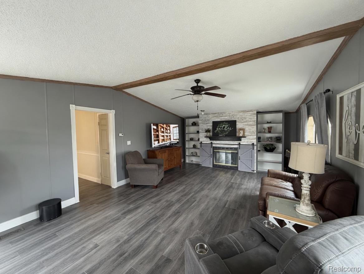 6988 McKean Road Ypsilanti, MI 48197 - Photo 3 of 31 Living room with dark wood-style flooring, a fireplace, beamed ceiling, ceiling fan, and built in features