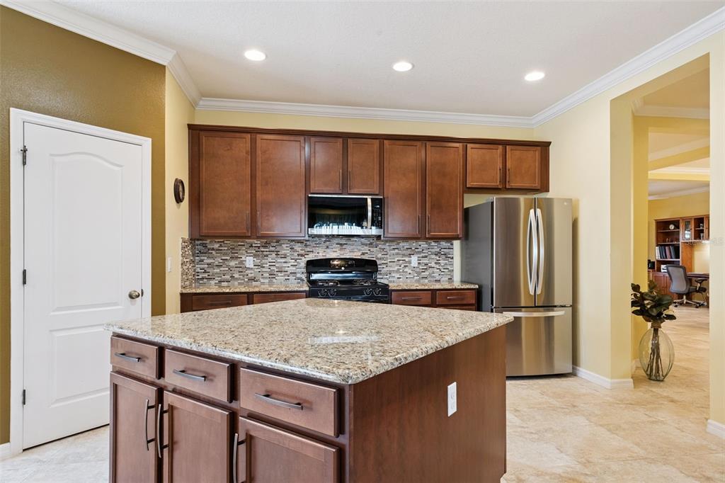 12332 Hammock Pointe Circle Clermont, FL 34711 - Photo 21 of 39 a kitchen with kitchen island a refrigerator and a stove top oven