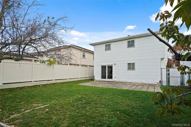 a backyard of a white house with potted plants and a large tree
