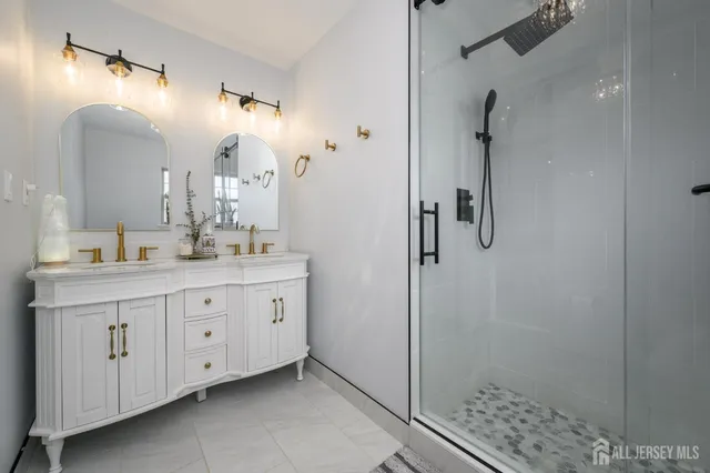 a spacious bathroom with a double vanity sink a mirror and a shower