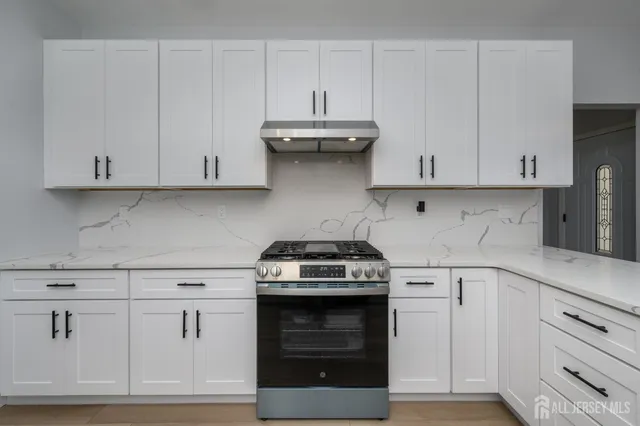 a kitchen with white cabinets and a stove with a sink