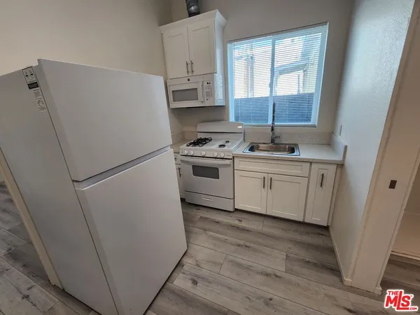 a kitchen with a sink a refrigerator a window and cabinets