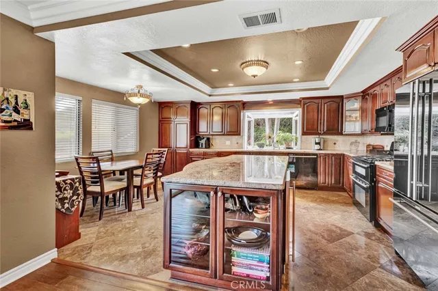 a kitchen with stainless steel appliances granite countertop a stove top oven a sink a dining table and chairs with wooden floor