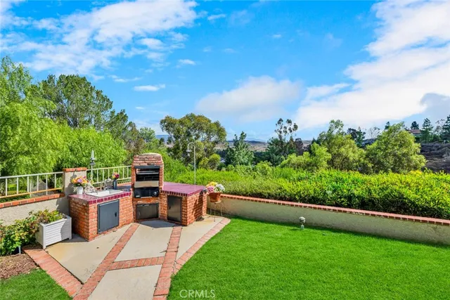 a view of a patio with couches plants and large trees