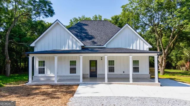 a view of a house with small yard plants and large tree