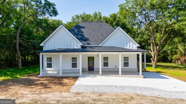a view of a house with a yard plants and large tree