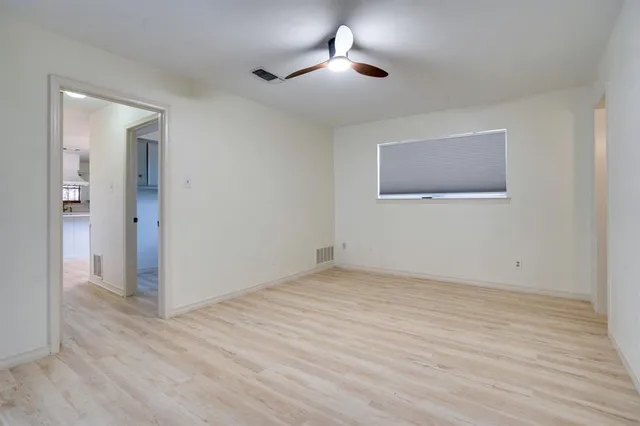 a view of an empty room with wooden floor and a chandelier fan